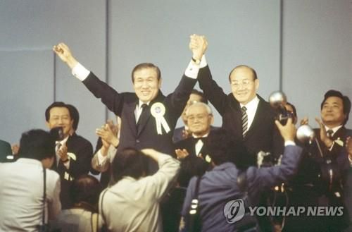 개그맨 김병조가 중간 진행을 맡은 민정당 전당대회 (서울=연합뉴스) 1987년 6월10일 민정당 전당대회에서 대통령 후보로 지명된 노태우 대표(왼쪽)가 전두환 대통령과 손을 맞잡고 대의원들의 환호에 답하는 모습. [연합뉴스 자료사진]