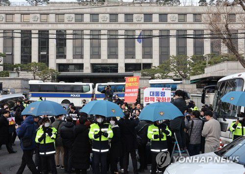 충돌 우려로 우산 펼쳐 든 경찰들(서울=연합뉴스) 이진욱 기자 = 윤석열 대통령 탄핵심판 선고일 발표가 늦어지고 있는 가운데 20일 서울 종로구 헌법재판소 앞에서 경찰들이 탄핵 찬반 시위자들과 기자회견 참석자들 간의 충돌 등을 우려해 우산을 펼쳐 들고 있다. 2025.3.20 cityboy@yna.co.kr