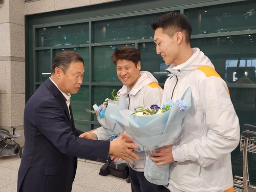 꽃다발 받는 우상혁(영종도=연합뉴스) 하남직 기자 = 2025 난징 세계실내육상선수권 남자 높이뛰기에서 우승한 우상혁(오른쪽)이 22일 인천국제공항에서 김동주(왼쪽) 대한육상연맹 수석부회장으로부터 꽃다발을 받고 있다. 가운데는 김도균 용인시청 감독 겸 국가대표 코치.