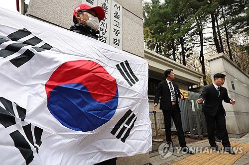 윤석열 응원하는 지지자(서울=연합뉴스) 김도훈 기자 = 내란 우두머리 혐의로 기소된 윤석열 전 대통령의 첫 형사재판이 열린 14일 서울 서초구 서울중앙지방법원 앞에서 한 윤 전 대통령 지지자가 태극기를 들고 서 있다. 2025.4.14 superdoo82@yna.co.kr