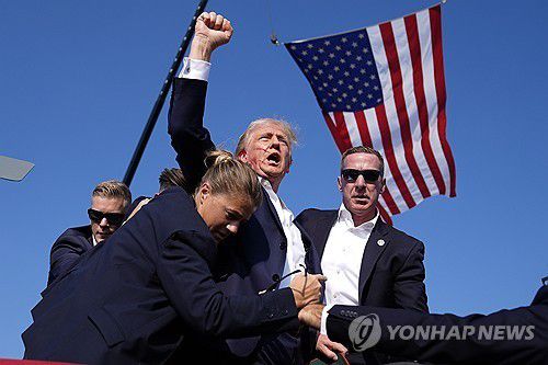 작년 암살 시도에서 살아남은 뒤 주먹 치켜올린 트럼프 대통령(버틀러 AP=연합뉴스) 지난해 7월 13일(현지시간) 미 펜실베이니아주 버틀러 유세 도중 암살 시도 직후 트럼프가 경호원들에 둘러싸인 채 주먹을 위로 치켜들고 있다.