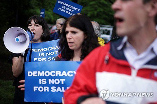 트럼프 밈코인 행사에 항의하는 시위대(스털링<미 버지니아주> AFP=연합뉴스) 2025년 5월 22일 미국 버지니아주 스털링의 트럼프 내셔널 골프 클럽에서 열리는 비공개 만찬 행사에 항의하는 시위 참가자들이 골프 클럽 바깥에서 시위를 벌이고 있다. (Getty Images via AFP) 2025.5.24.