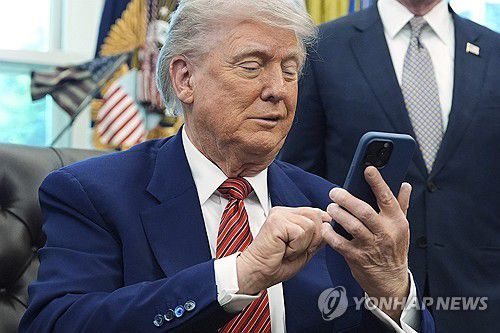 집무실 문답 중 전화가 울리자 벨 소리를 무음으로 바꾸는 트럼프[워싱턴 AP=연합뉴스. 재판매 및 DB 금지]