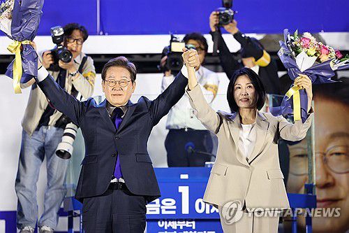 시민들 향해 두 팔 들어올리는 이재명 후보 내외(서울=연합뉴스) 김주성 기자 = 제21대 대통령 당선이 확실시되는 더불어민주당 이재명 대선 후보와 부인 김혜경 여사가 4일 서울 여의도 국회 인근에서 당 주최로 열린 국민개표방송 행사에 참석해 꽃다발을 받고서 시민들을 향해 두 팔을 들어올려 인사하고 있다. 2025.6.4 [공동취재] utzza@yna.co.kr