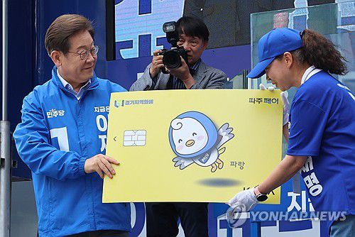 지역화폐 모형 전달받는 이재명 후보(파주=연합뉴스) 김주성 기자 = 더불어민주당 이재명 대선 후보가 20일 경기 파주시 금릉역 중앙광장에서 열린 유세에서 지역화폐 모형을 전달받고 있다. 2025.5.20 utzza@yna.co.kr