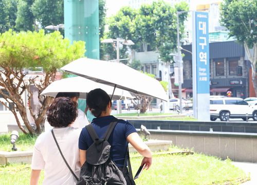 뜨거운 햇볕을 피하는 방법 (대구=연합뉴스) 박세진 기자 = 28일 대구 북구 대구역 앞 광장에서 시민들이 햇볕을 피하기 위해 양산을 쓰고 이동하고 있다. 2025.6.28 psjpsj@yna.co.kr