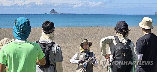 형제섬과 국토 최남단 마라도(제주=연합뉴스) 김호천 기자 = 26일 오전 2025 제주도 세계지질공원 산방산 용머리해안 지질트레일에 참가한 탐방객들이 황우치 해변에서 형제섬과 그 뒤쪽 국토 최남단 마라도 등에 대한 해설사의 설명을 듣고 있다. 2025.7.26 khc@yna.co.kr