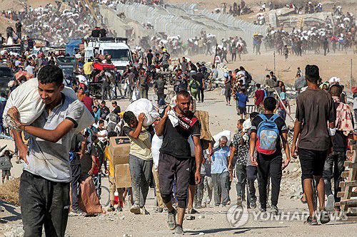 지난 22일(현지시간) 가자인도주의재단(GHF) 배급소에서 받은 인도적 구호 물품을 들고 가자지구 중부 넷자림 회랑을 지나는 팔레스타인 주민들.[AFP=연합뉴스. 재판매 및 DB 금지]