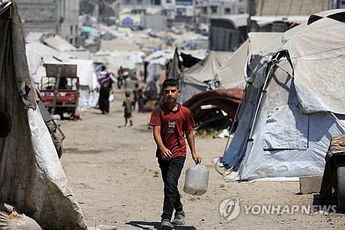 지난 22일(현지시간) 가자지구 가자시티에서 한 소년이 통을 들고 걸어가고 있다.[로이터=연합뉴스. 재판매 및 DB 금지]