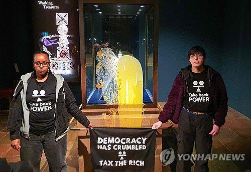 시위대에 봉변 당한 英왕실 왕관 진열장영국 시민단체 '테이크 백 파워' 활동가들이 런던탑에서 값비싼 영국 왕실 왕관 진열장에 음식물을 뿌린 뒤 '민주주의가 바스러졌다. 부자들에게 과세하라'라는 구호가 적힌 펼침막을 들고 있다. ['테이크 백 파워' 제공/AFP=연합뉴스. 재판매 및 DB 금지]