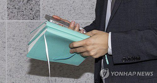 '주식 차명거래' 이춘석 의원실 폐지함에서 발견된 수첩(서울=연합뉴스) 황광모 기자 = 서울경찰청 금융범죄수사대 전담수사팀 관계자가 11일 주식 차명거래 혐의를 받는 이춘석 의원의 국회 사무실 압수수색 진행 도중 취재진이 이 의원실 출입문 앞 폐지함에서 발견한 수첩을 전달받은 뒤 이동하고 있다. 2025.8.11 hkmpooh@yna.co.kr
