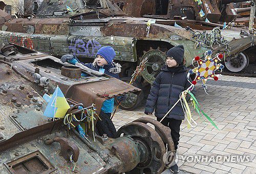성탄절인 25일 우크라이나 소년이 키이우 시내에서 부서진 러시아 전차에 크리스마스 상징물을 부착하고 있는 모습[EPA 연합뉴스 자료사진]