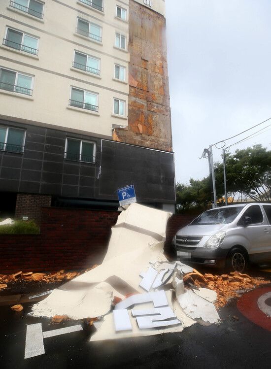 제8호 태풍 ‘바비’가 제주를 강타한 26일 오후 제주시 동광로 한 아파트 외벽 마감재가 떨어져 주차된 차량을 덮치고 있다. 연합뉴스