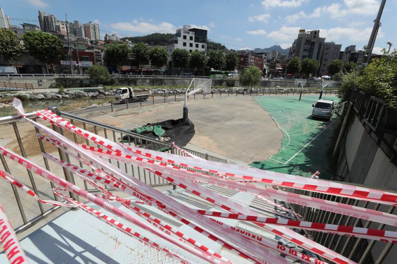 16일 낮 폭우로 범람했던 도림천 상류 농구코트가 파손된 상태로 놓여 있는 가운데 관악구 관계자들이 복구 작업을 하고 있다. 신소영 기자