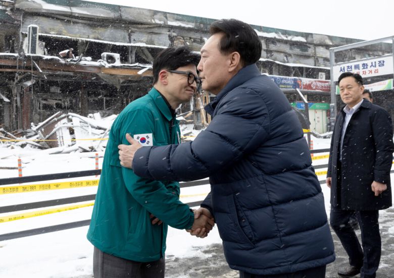 윤석열 대통령이 23일 충남 서천군 서천읍 서천특화시장 화재 현장에서 국민의힘 한동훈 비상대책위원장과 만나 악수하고 있다. 대통령실 제공
