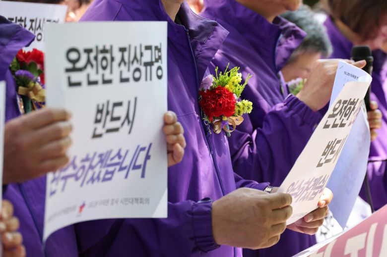 10·29 이태원 참사 유가족들이 8일 오전 서울 중구 서울광장 분향소 앞에서 열린 ‘10·29 이태원 참사 온전한 진상규명을 위해 거리에서 맞는 두 번째 어버이날 행사’에서 학생들에게 카네이션을 받은 뒤 손팻말을 들어 보이고 있다. 신소영 기자