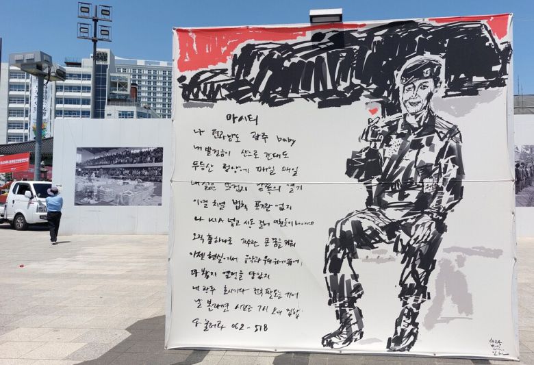 군 복무 중인 비티에스 멤버 제이홉이 하트를 띄우는 모습과 비티에스의 히트곡 ‘마시티’의 광주 관련 가사가 등장하는 박성완 작가의 거리그림 ‘마시티’. 광주 옛 도청건물 부근의 5·18민주광장에서 ‘오월정신, ‘꽃’ 피우다’란 제목으로 전시 중인 청년작가들의 오월 거리그림전에 나온 화제의 출품작이다. 노형석 기자