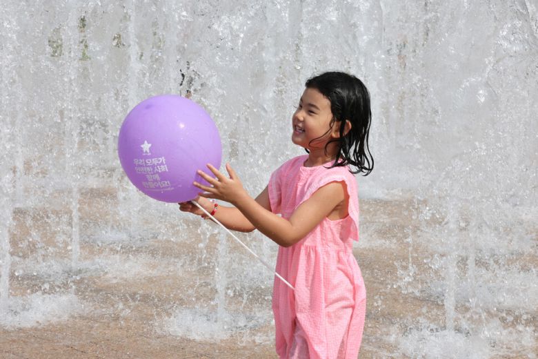 한 어린이가 15일 오후 서울 중구 서울광장에서 유가족이 나눠준 보라색 풍선을 들고 바닥분수에서 물놀이하고 있다. 김영원 기자