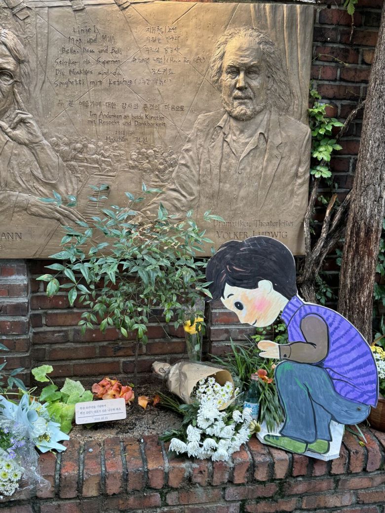 지난 2021년 3월15일 학전 30주년을 기념해 김민기 학전 대표가 심은 나무. 나무 옆에서 그림판 속 작은 아이가 흰 국화꽃을 내려다 보고 있다. 서정민 기자