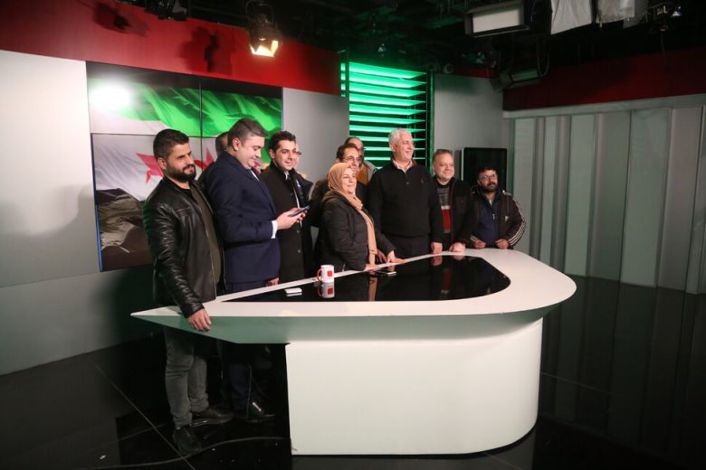 시리아 국영 텔레비전 뉴스 앵커들이 8일 반군이 수도 다마스쿠스를 점령한 뒤 다마스쿠스 스튜디오에서 시리아 야당 깃발 앞에서 사람들과 기념사진을 찍고 있다. 이날 다마스쿠스에 입성한 반군은 텔레비전 성명을 통해 ‘다마스쿠스의 해방과 바샤르 아사드의 전복\'을 선언하고 모든 수감자를 석방한다고 발표했다. 다마스쿠스/EPA연합뉴스