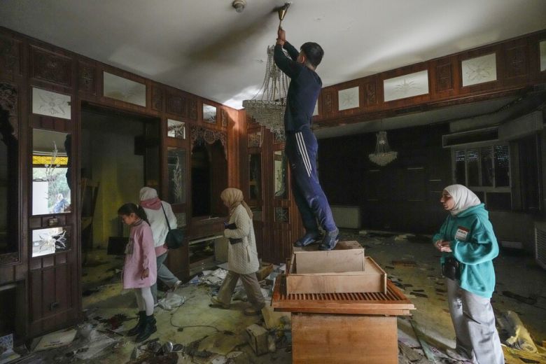 시리아 다마스쿠스 말리케 지역에 있는 대통령 바샤르 아사드의 사저에서 8일 한 남성이 천장에 달린 조명등을 떼어가려 하고 있다. AP 연합뉴스