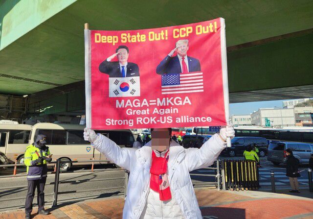 서울 한남동 대통령 관저 부근에서 윤 대통령 지지자가 윤석열 대통령과 트럼프 대통령을 동일시하면서 ‘중국 공산당(CCP)은 꺼져라’라고 쓰인 펼침막을 들고 서 있다. 박고은 기자