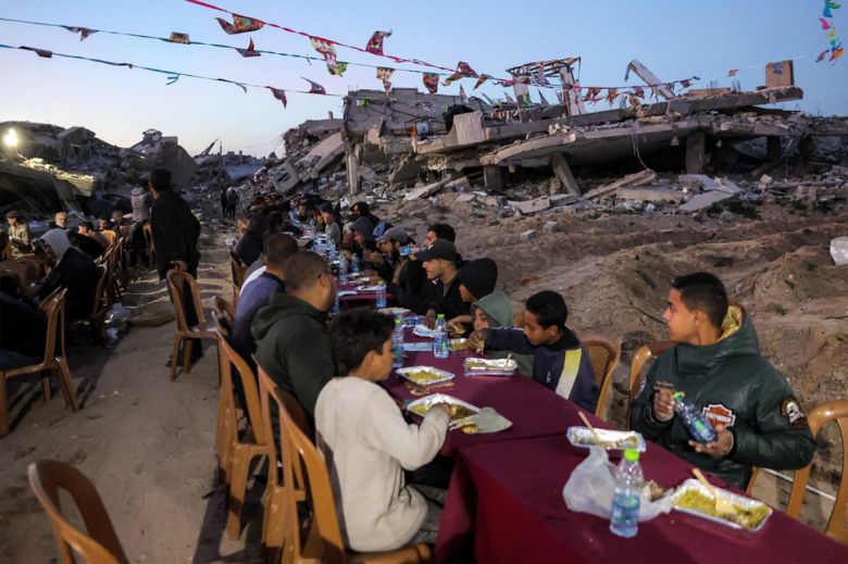 이스라엘과 하마스 간의 전쟁이 계속되는 가운데, 가자지구 가자시티의 알다두 지역에서 라마단 이튿날인 2일 팔레스타인 주민들이 파괴된 건물 잔해 옆에 모여 금식을 깨는 이프타르 식사를 하고 있습니다. AFP 연합뉴스