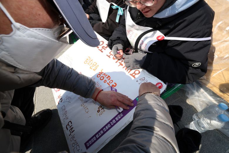 ‘부산 윤석열 퇴진 대학생 행동 준비위원회’ 회원들이 단식농성 5일째를 맞은 19일 오후 서울 종로구 광화문 앞 이들 농성 텐트 앞에서 만든 손팻말에 시민이 윤석열 대통령 퇴진을 촉구하는 리본을 붙여주고 있다. 김영원 기자 forever@hani.co.kr