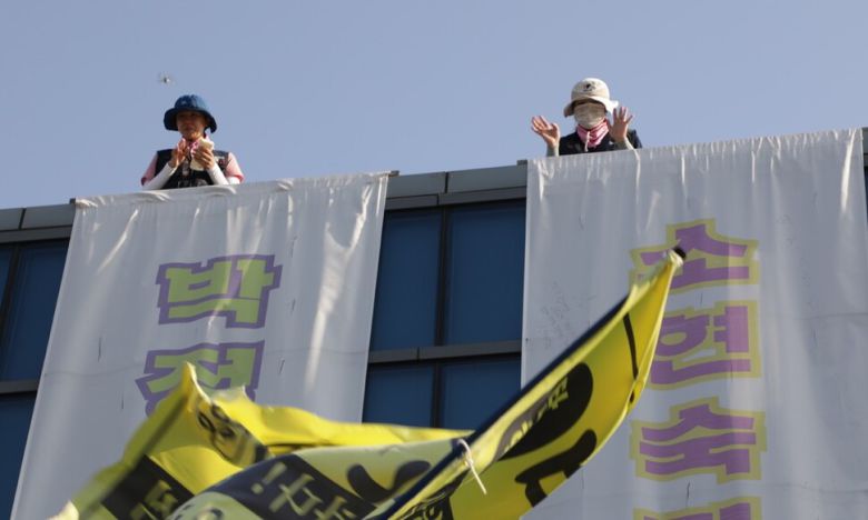 한국옵티칼하이테크 정리해고자 박정혜(왼쪽)씨와 소현숙씨가 희망버스 문화제가 열린 26일 오후 고공농성장에서 아래쪽을 향해 손을 흔들고 있다. 전국금속노조 제공