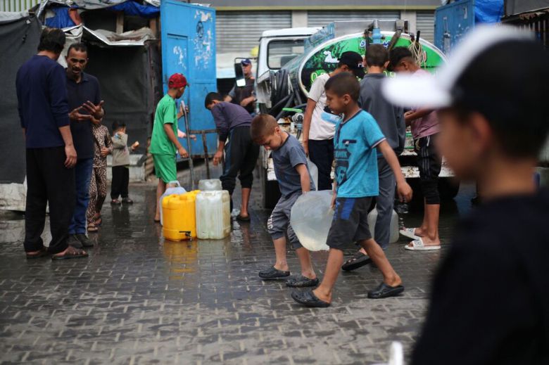 28일(현지시각) 팔레스타인 소년들이 가자지구 중부 브레이즈 난민캠프에서 물을 담아 걸어가고 있다. 브레이즈/AFP 연합뉴