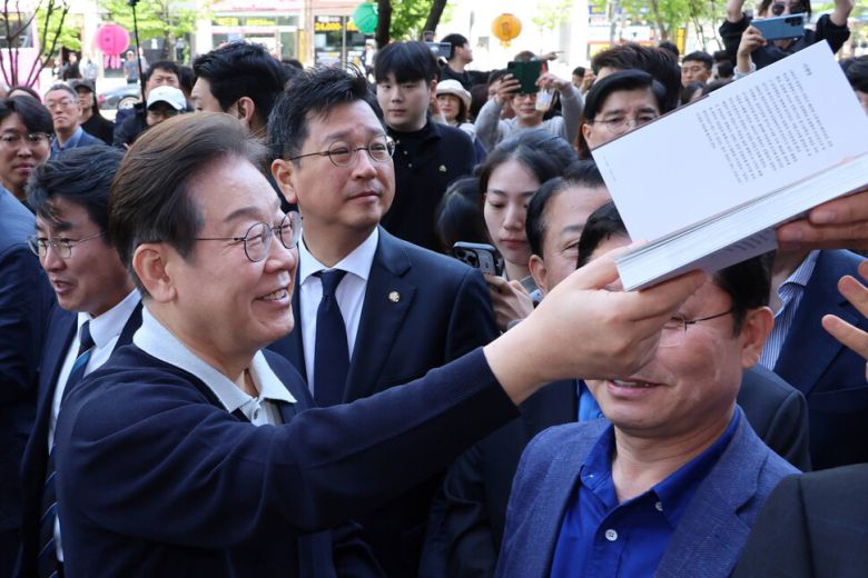 이재명 더불어민주당 대통령 후보가 4일 경북 예천군 도청신도시를 찾아 저서에 사인을 해주고 있다. 연합뉴스