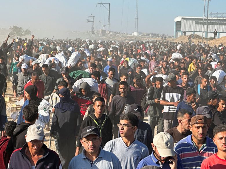 29일 가자지구 남부 칸유니스에서 주민들이 미국이 지원하는 가자인도주의재단(GHF)으로부터 받은 구호물품을 들고 걸어가고 있다. 칸유니스/로이터 연합뉴스