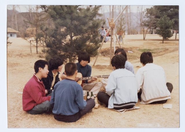 1979년 이재명 대통령 당선자(왼쪽 첫째)가 시계 만드는 오리엔트 공장에 다닐 때 남이섬으로 야유회를 가 둥글게 앉아 노래하는 모습. 더불어민주당 제공