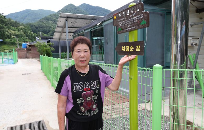 마을을 위해 땅을 내놔 마을 길을 넓게 한 차정순씨가 ‘차정순길’ 현판을 가리키고 있다. 괴산군 제공