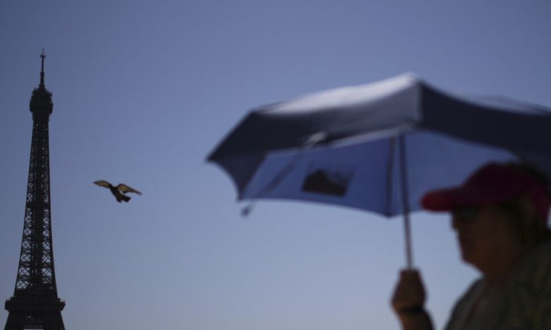 폭염이 기승을 부린 지난 2일(현지시각) 프랑스 파리 에펠탑 앞에서 시민이 양산을 쓰고 지나가고 있다. AP 연합뉴스
