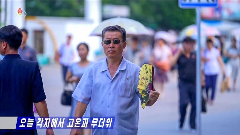 무더위가 지속되는 북한 평양에서 한 남성이 부채질을 하며 더위를 식히고 있다. 조선중앙티브이(TV) 화면 갈무리