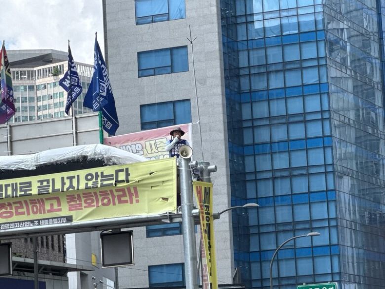 22일 세종호텔 앞 도로 한복판에 놓인 10ｍ 높이의 철제 구조물 위에서 농성을 벌이고 있는 세종호텔 해고 노동자 고진수씨가 원로들의 응원해 화답하고 있다. 정봉비 기자