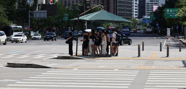 최고 체감온도가 35도 안팎으로 오르며 전국이 매우 무더운 날씨를 보인 27일 오후 서울 종로구 광화문의 건널목 그늘막 아래에 시민들이 옹기종기 모여 햇빛을 피하고 있다. 김혜윤 기자 unique@hani.co.kr