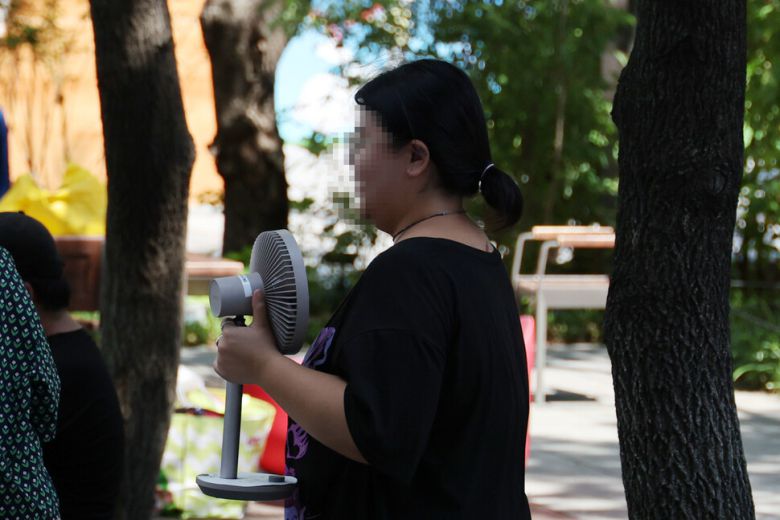 전국 대부분 지역에 폭염경보가 발효된 27일 오후 서울 종로구 광화문광장 그늘에서 한 시민이 탁상용 선풍기를 들고 있다. 김혜윤 기자 unique@hani.co.kr