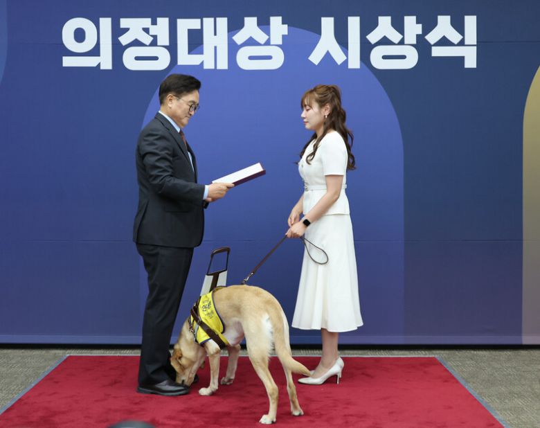 국민의힘 김예지 의원이 지난달 11일 서울 여의도 국회에서 열린 제5회 대한민국 국회 의정대상 시상식에서 우원식 국회의장으로부터 우수입법의원 의정대상을 받고 있다. 가운데는 김 의원의 안내견인 태백이. 연합뉴스