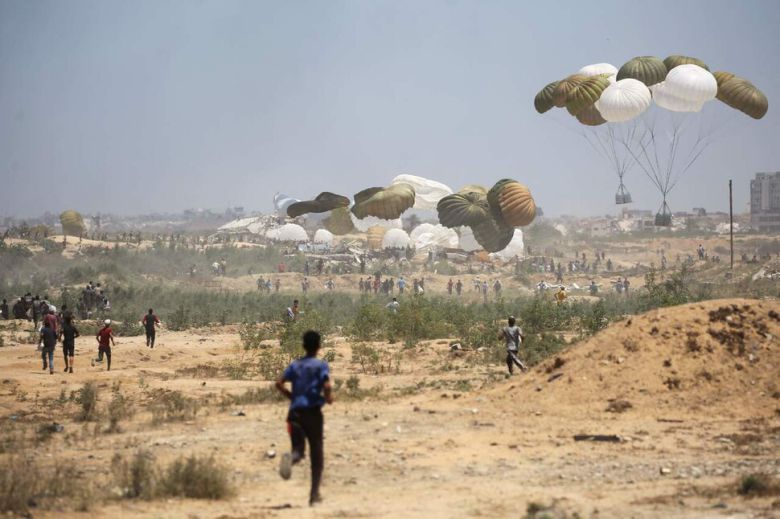 6일(현지시각) 가자지구 중앙 누세이라트 지역에 공중 투하 중인 구호품을 따라 가자 주민들이 달리고 있다. 누세이라트/AFP 연합뉴스