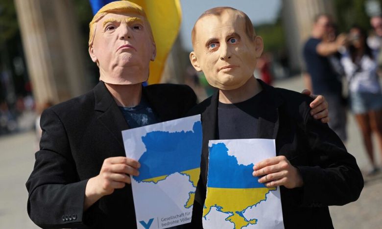 14일 독일 베를린 브란덴부르크 문 앞에서 미국 대통령 도널드 트럼프와 러시아 대통령 블라디미르 푸틴으로 분장한 활동가들이 우크라이나 지도를 찢은 뒤 포즈를 취하고 있다. 이날 이곳에서는 트럼프 대통령에게 푸틴과의 회담에서 우크라이나를 팔아넘기지 말 것을 촉구하는 시위가 열렸다. AFP연합뉴스