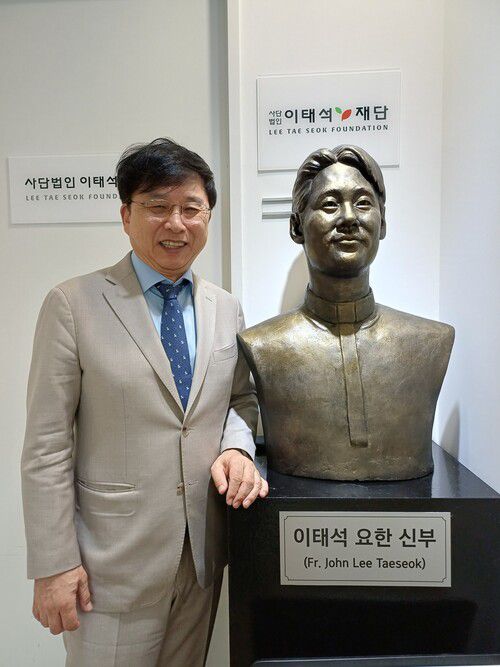 구수환 이태석재단 이사장이 재단 사무실 앞의 이태석 신부상 옆에서 사진 포즈를 취하고 있다. 김아리 객원기자