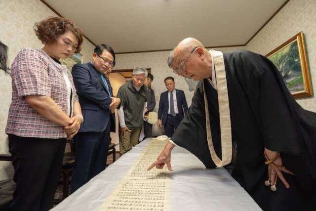지난 7월1일 일본 교토의 고찰 쇼렌인에서 백제 무왕의 익산 천도 기록이 담긴 고문헌 ‘관세음응험기’ 실물이 처음 한국 관계자들에게 공개됐다. 정헌율 익산시장을 비롯한 시 관계자들과 문화유산 전문가들이 문헌을 실견하면서 쇼렌인 주지의 설명을 듣고 있다. 익산시 제공