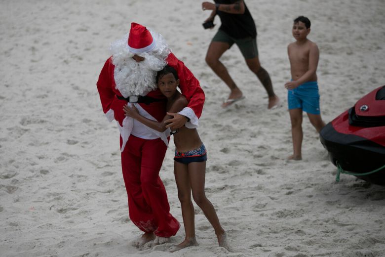 4일(현지시각) 한 브라질 소년이 크리스마스 선물을 나눠주기 위해 제트 스키를 타고 리우데자네이루의 코파카바나 해변에서 열린 어린이 행사에 도착한 산타클로스 복장을 한 소방관을 껴안고 있다.리우데자네이루/AP 연합뉴스