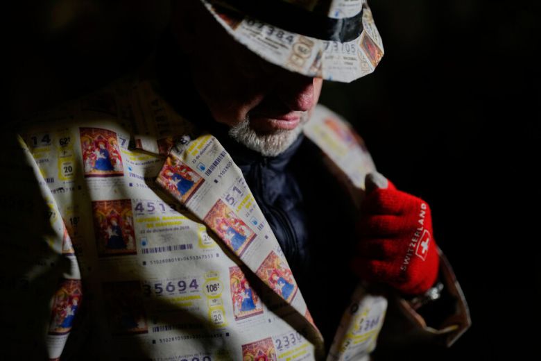 복권 무늬의 모자와 외투를 착용한 관람객이 22일 스페인 마드리드의 테아트로 레알에서 열린 연례 크리스마스 복권 추첨 행사 ‘엘 고르도’의 시작을 기다리고 있다. 마드리드/AP 연합뉴스