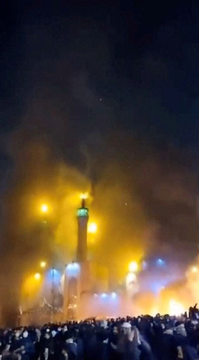 이란 테헤란에서 반정부 시위가 확산되는 가운데 이슬람 사원 모스크에서 연기가 피어오르는 것을 시위대가 지켜보고 있다. 9일 공개된 소셜미디어 영상에서 로이터 통신이 갈무리한 화면이며 촬영 시점은 확인할 수 없다. 다만 이란 국영매체는 9일 해당 영상 속 모스크가 불에 탔다고 보도했다. 로이터 통신