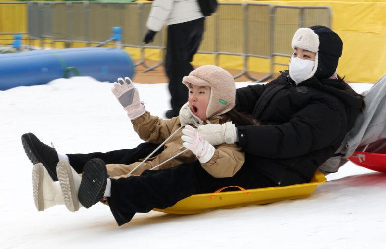 겨울 테마파크 2026 노원 눈썰매장 장애인 가족 초청 행사가 열린 12일 오전 서울 노원구 서울과학기술대학교 종합운동장에서 어린이가 보호자와 눈썰매를 타고 있다. 김영원 기자 forever@hani.co.kr
