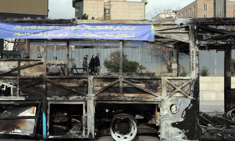 15일 이란 수도 테헤란의 거리에 불에 탄 버스 뒤로 시민들이 걸어가고 있다. 이란 군경이 지난 주말 사이 반정부 시위에 대한 유혈 진압의 강도를 높이며 이번주 들어 시위가 한풀 꺾였다는 보도들이 전해지고 있다. EPA 연합뉴스