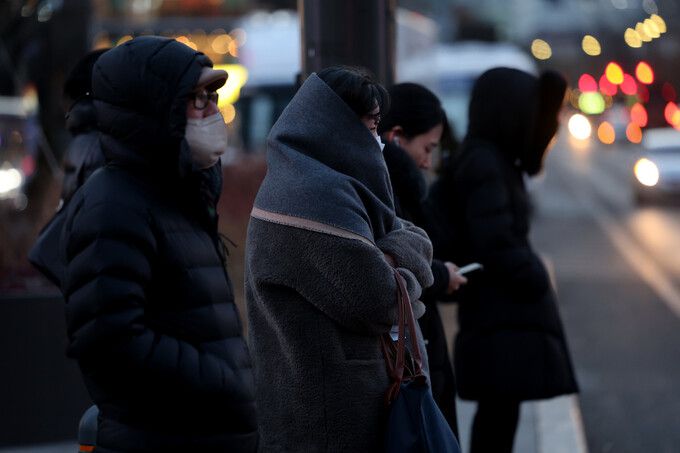 절기 대한(大寒)을 하루 앞두고 한파주의보가 예고된 19일 저녁 서울 종로 광화문 네거리에서 두꺼운 외투를 입은 시민들이 횡단보도에서 신호를 기다리고 있다. 연합뉴스